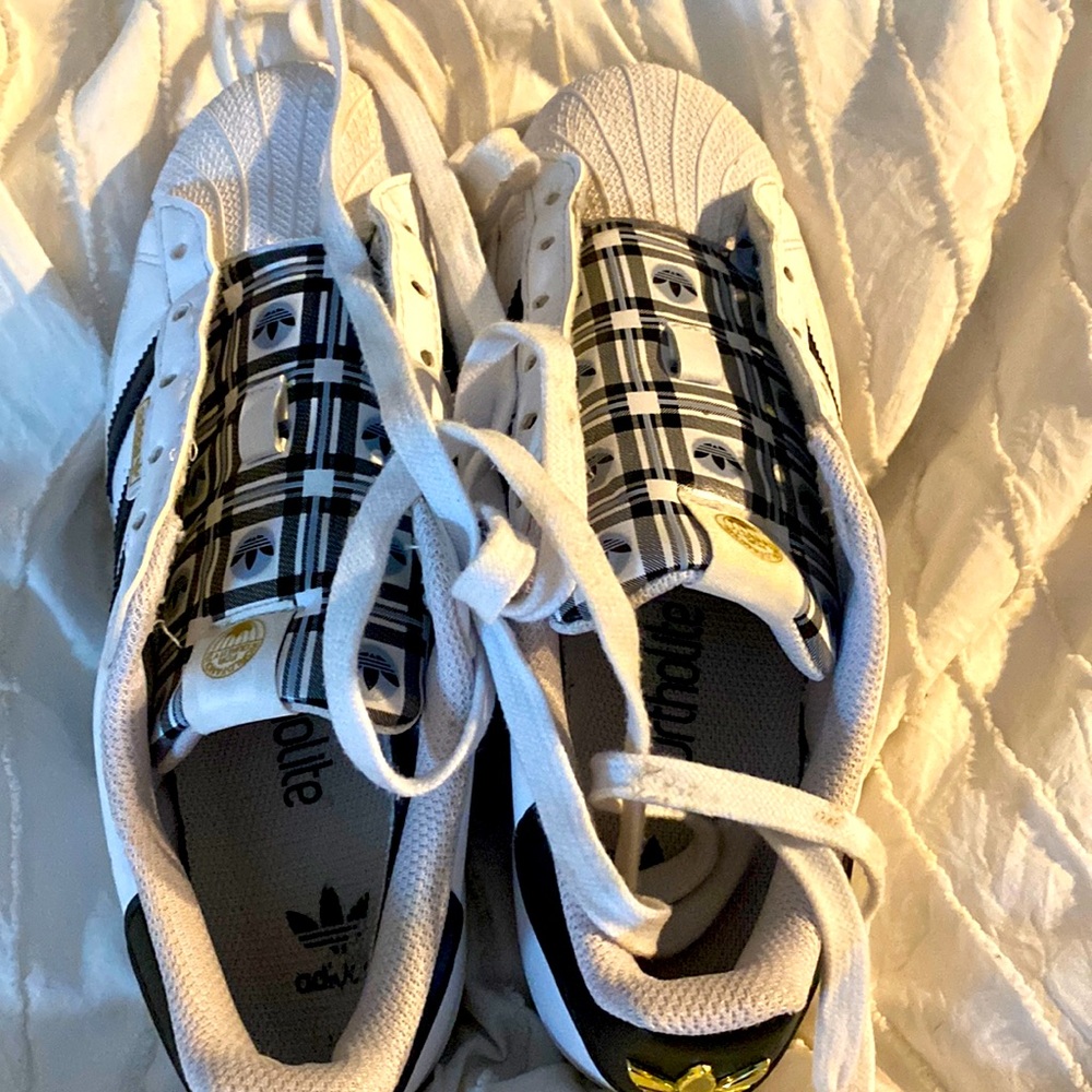 Woman’s White Shell Toe Adidas , with black, gold and plaid tongue. Size 6